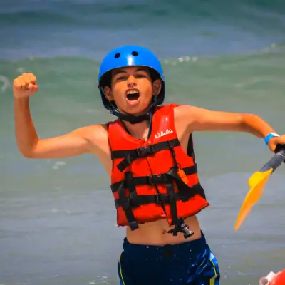 young kid in a life jacket and helmet flexing his muscles after a la jolla kayak rental