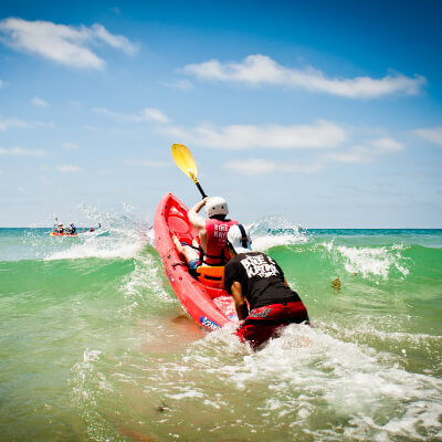 bike and kayak guide pushing a kayaker through the waves at la jolla shores
